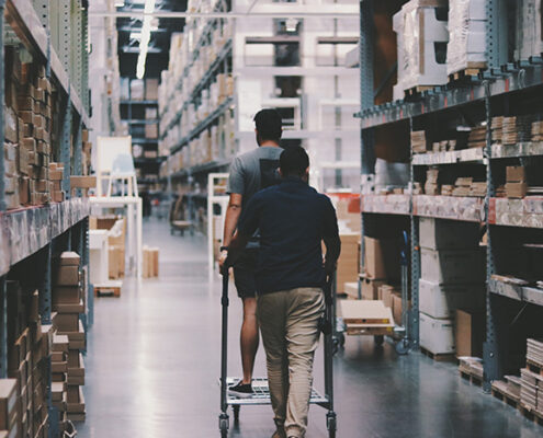 Two people walking down the aisles of a hardware store